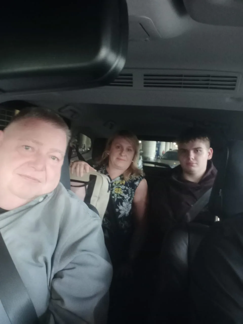 Family of three smiling in vehicle after evening event