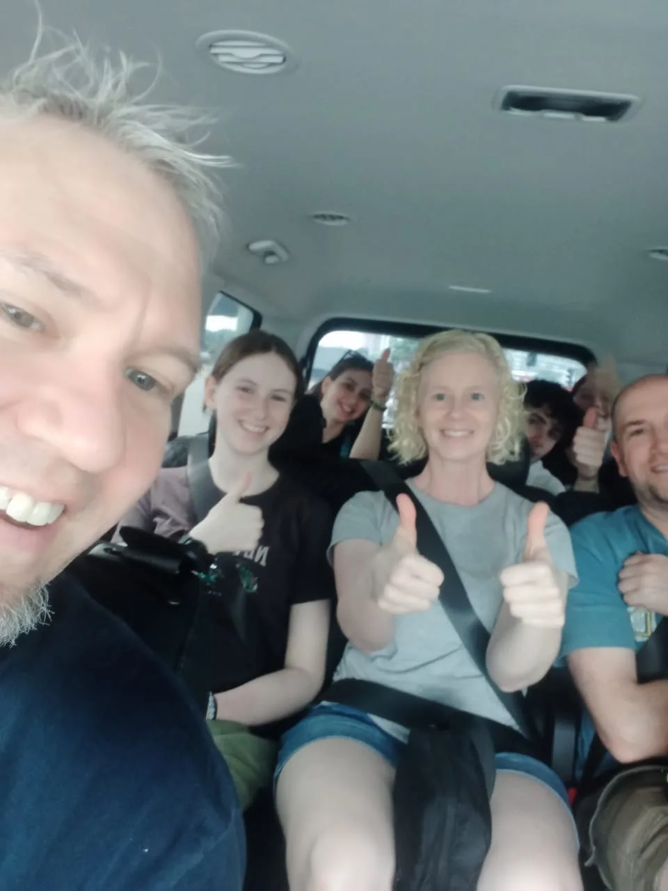 Large family giving thumbs up in spacious van