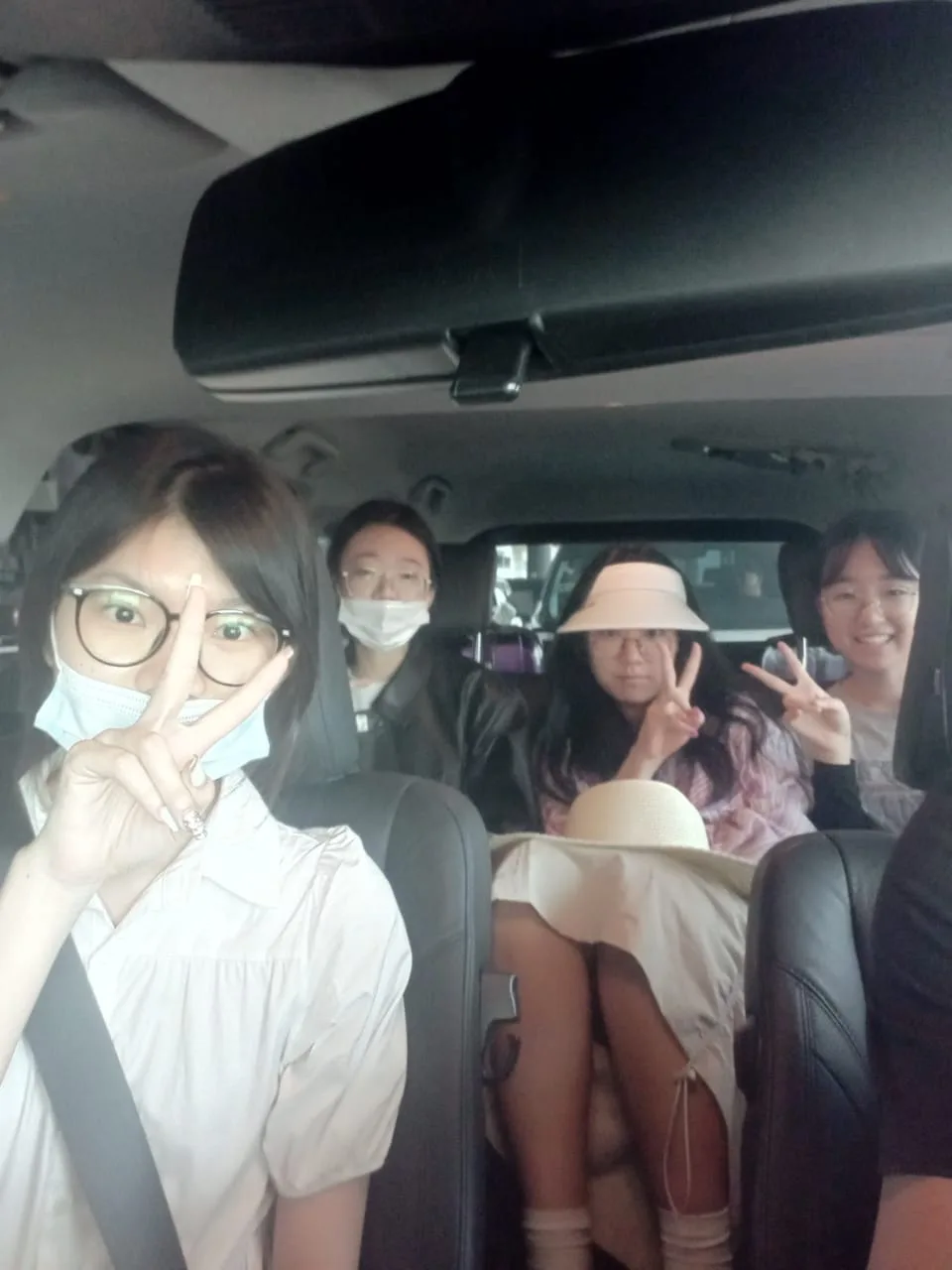 Four friends doing peace signs inside vehicle