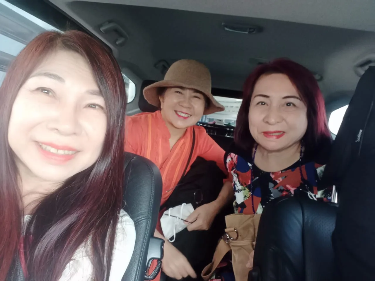 Three ladies smiling together during comfortable car ride