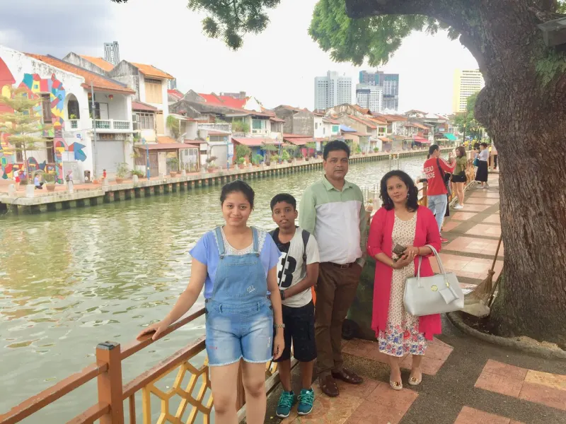 Family strolling along scenic Melaka River with colourful shophouses